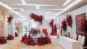 Un'area reception con una scrivania bianca, decorazioni floreali rosse e un moderno design del soffitto.