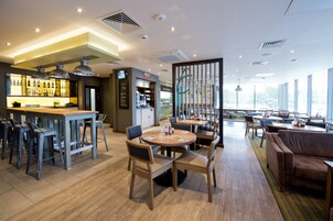 Un moderno vestíbulo de hotel con bar, comedor y zona de estar.
