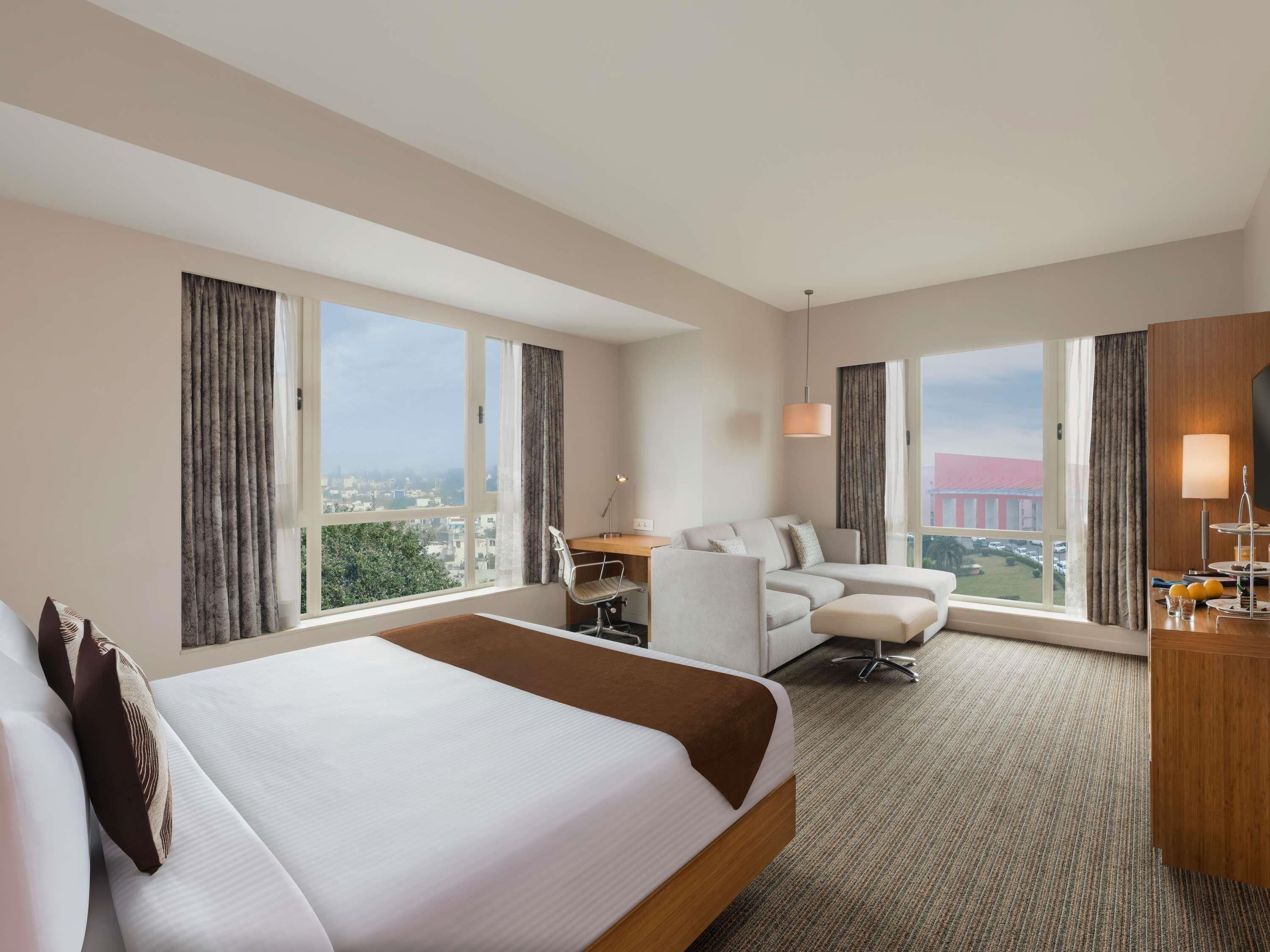 Habitación de hotel con una cama grande, un escritorio, un sofá y una televisión.