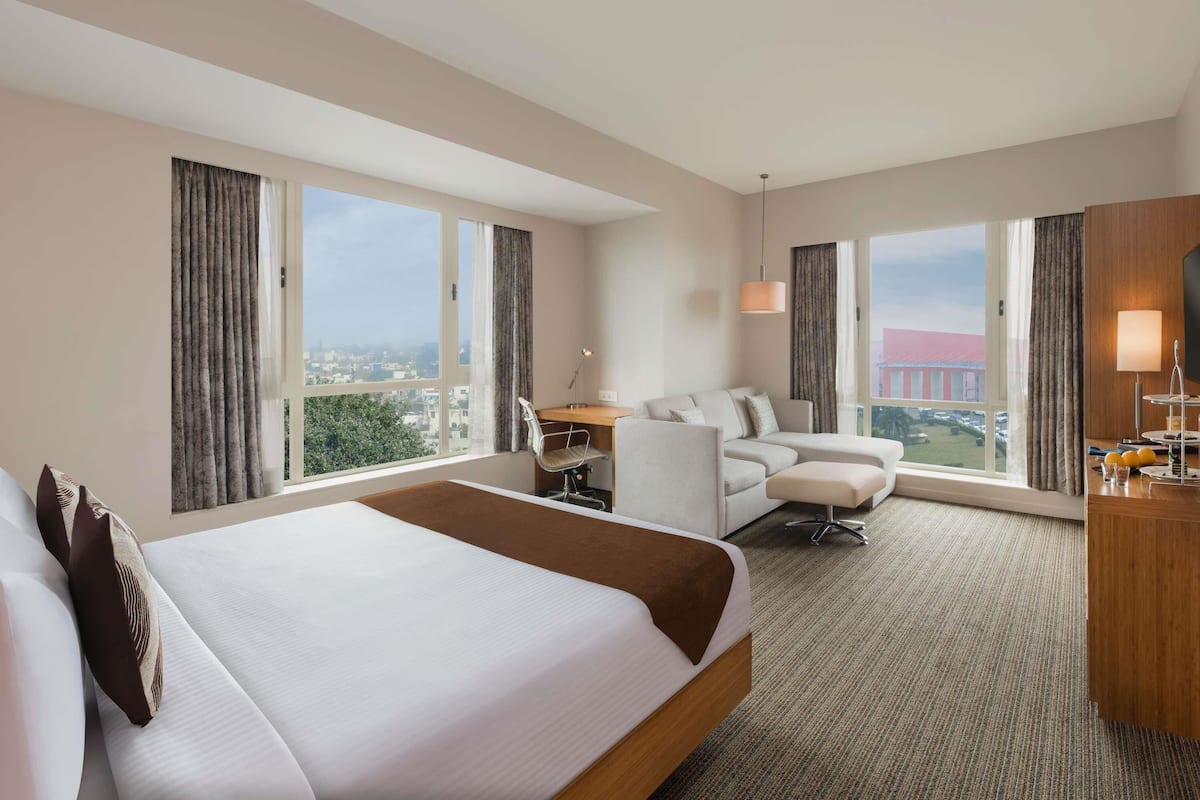 Habitación de hotel con una cama grande, un escritorio, un sofá y una televisión.