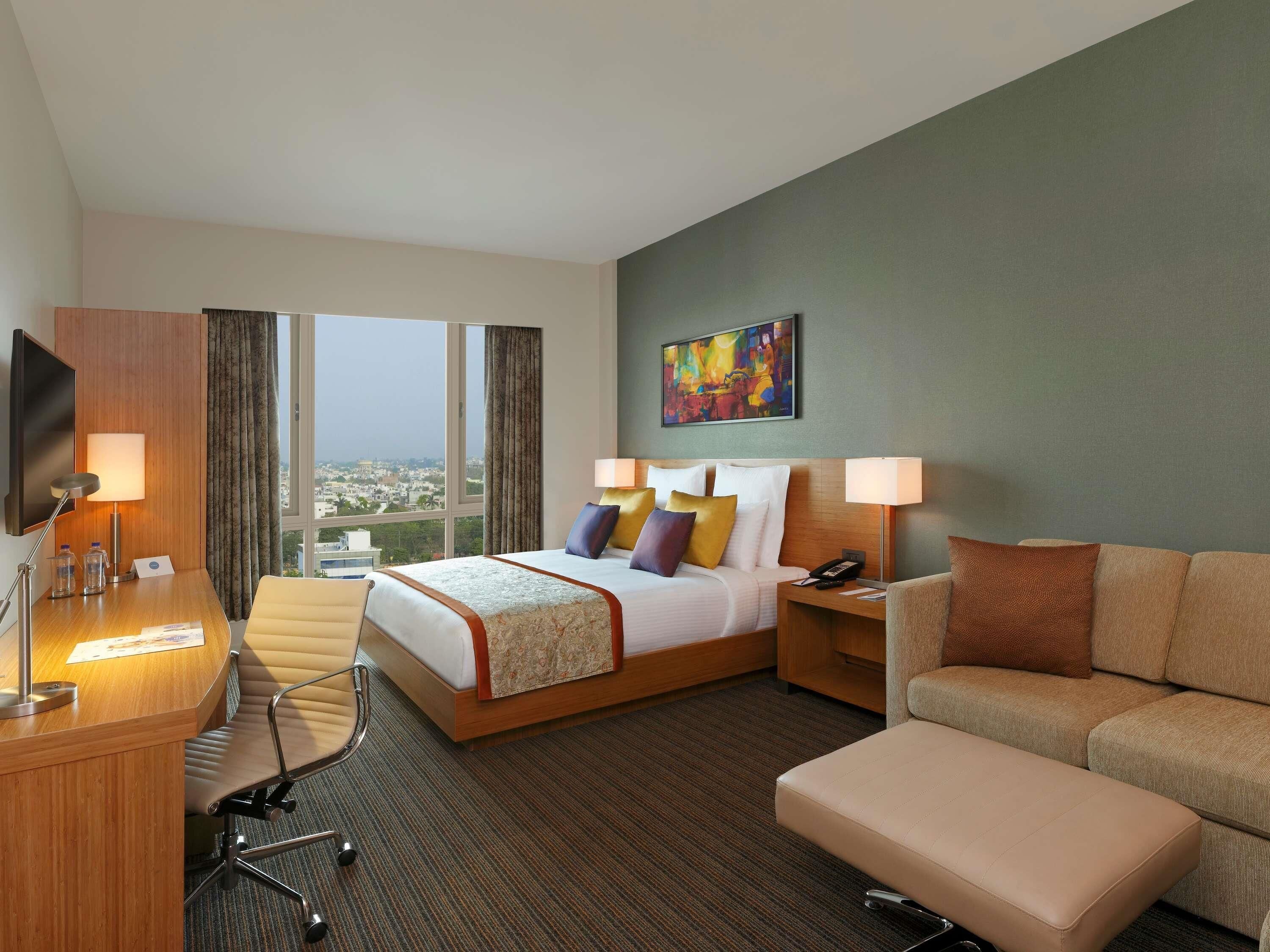 Una habitación de hotel con cama, escritorio, silla, sofá y televisor.