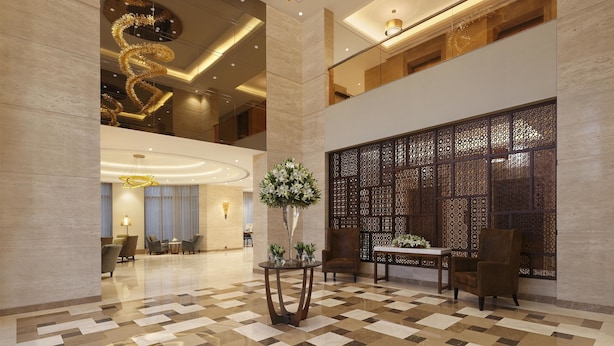 Un hall espacioso con piso a cuadros, un candelabro decorativo y una zona de estar con una mesa y sillas.