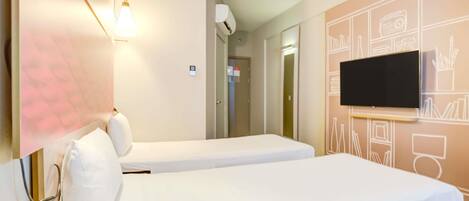 A hotel room with two single beds, a flat-screen TV mounted on the wall, and a wall-mounted air conditioning unit.