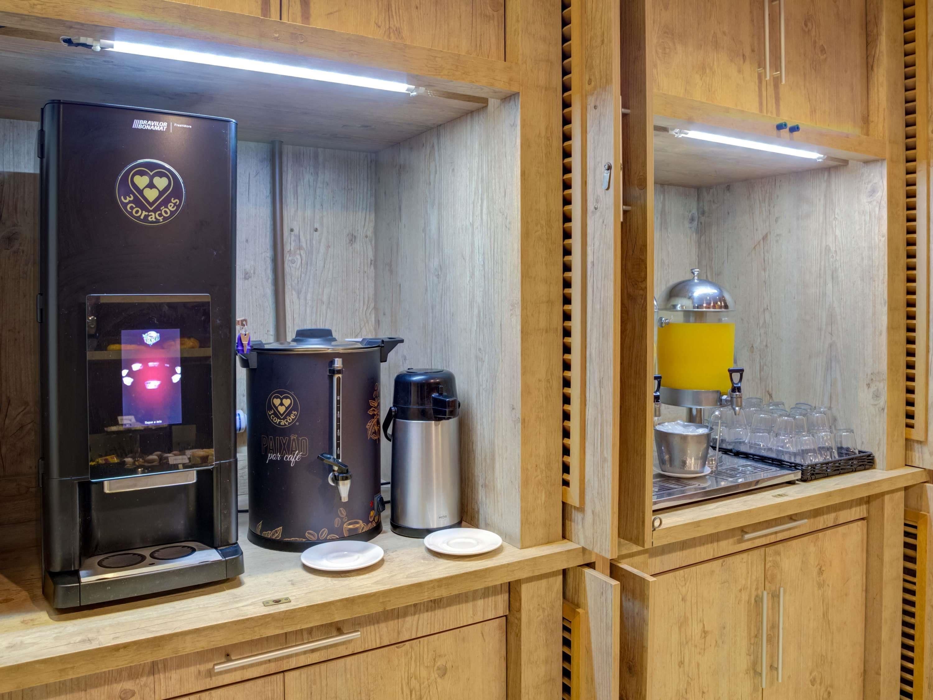 En kaffestation med kaffemaskine, kaffekande, termokande og et glasstik.