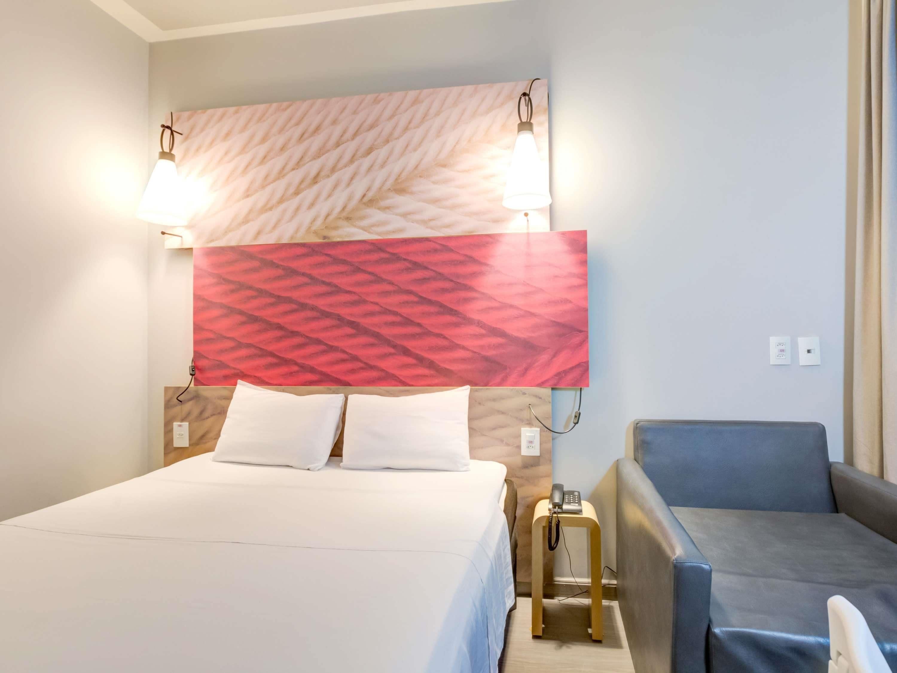 Une chambre d’hôtel avec un lit, un bureau avec un téléphone et un canapé.