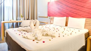 Habitación de hotel con cama, escritorio, lámpara, cortinas y pared con textura.