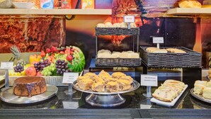 Un bufé con diversas opciones de comida, incluyendo un pastel de chocolate, pan de plátano y frutas frescas.