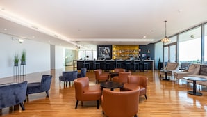Um hall amplo com assentos de couro, área de bar e grandes janelas com vista.