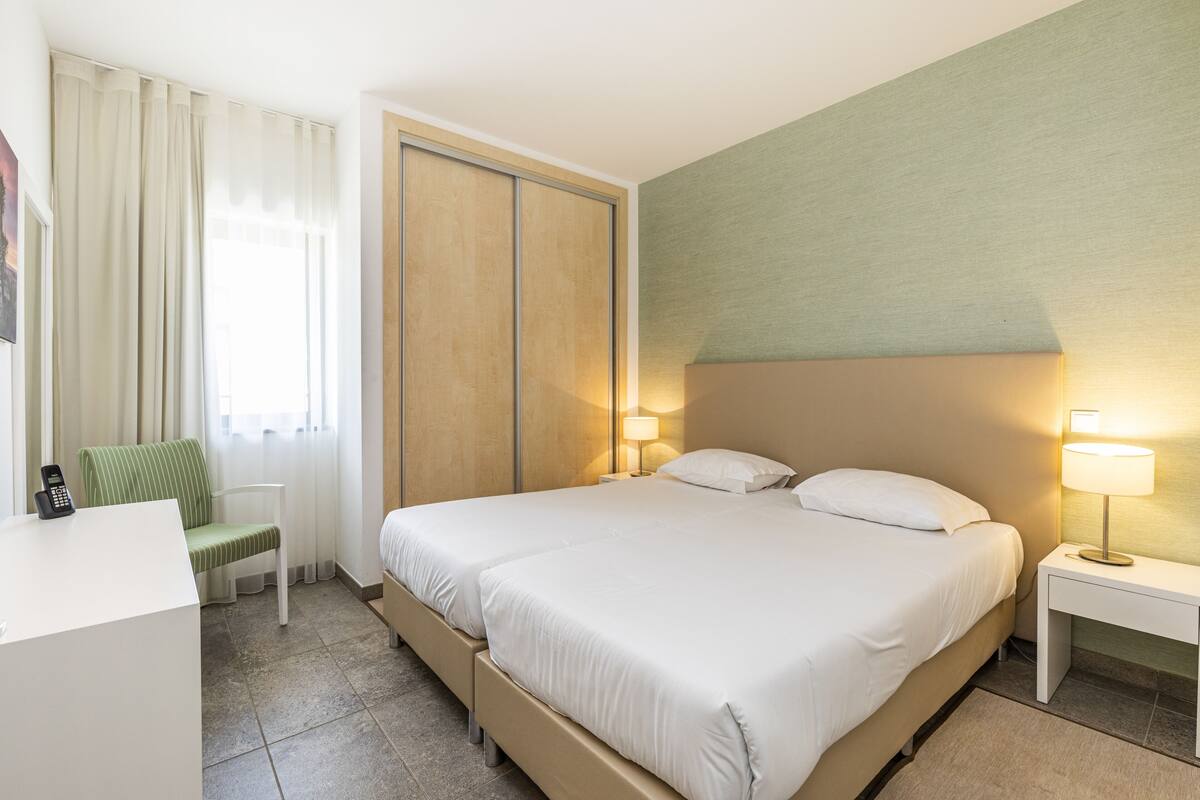 Une chambre d’hôtel comprenant un lit, des tables de chevet, une chaise et un bureau.