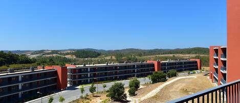 A multi-story hotel with a red facade, located in a hilly area with a clear view of the surrounding landscape.