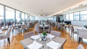 Uma ampla área de refeições com várias mesas e cadeiras, janelas grandes e um design moderno no teto.