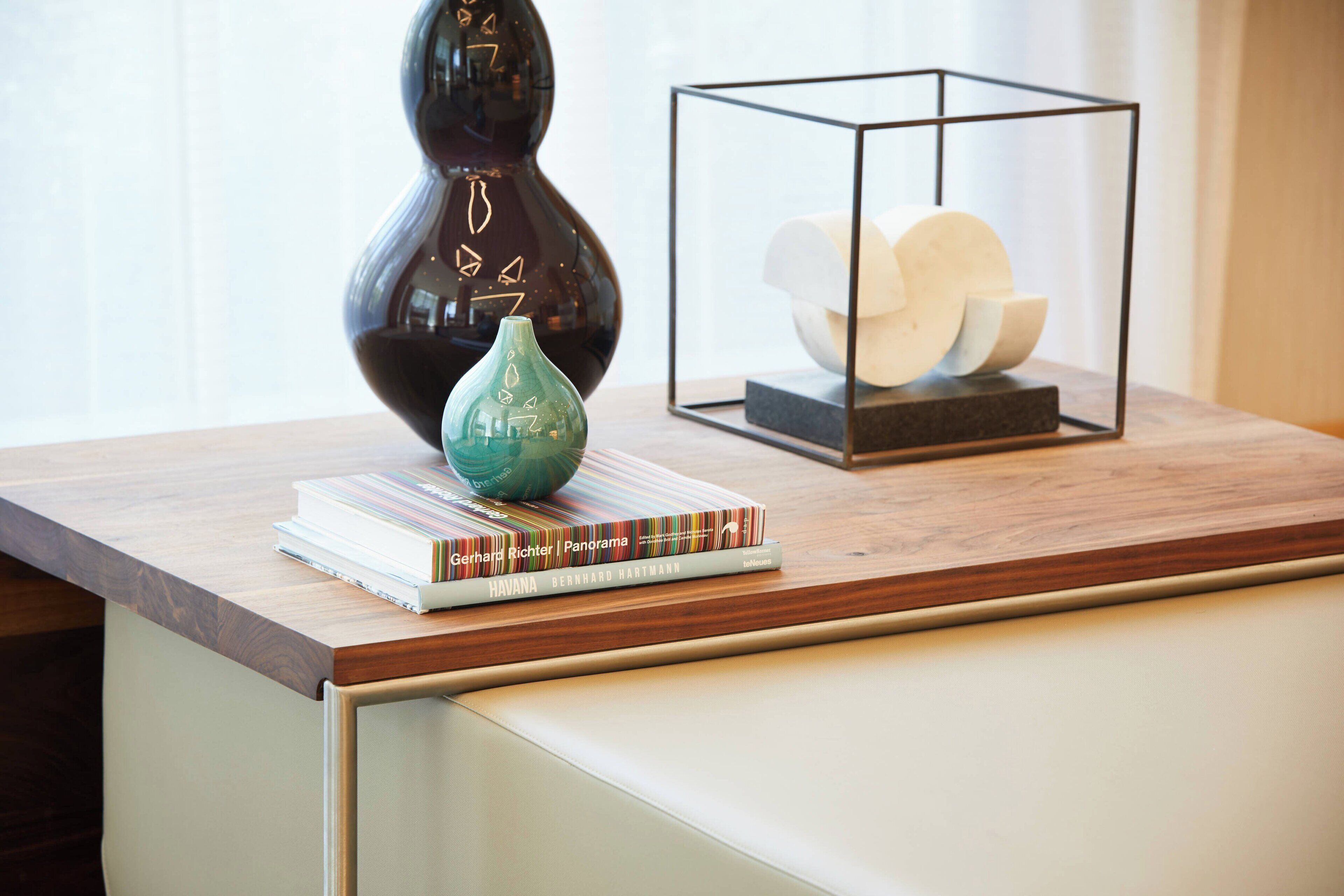 A wooden table with a vase, a book titled 'Havana', and a framed sculpture.