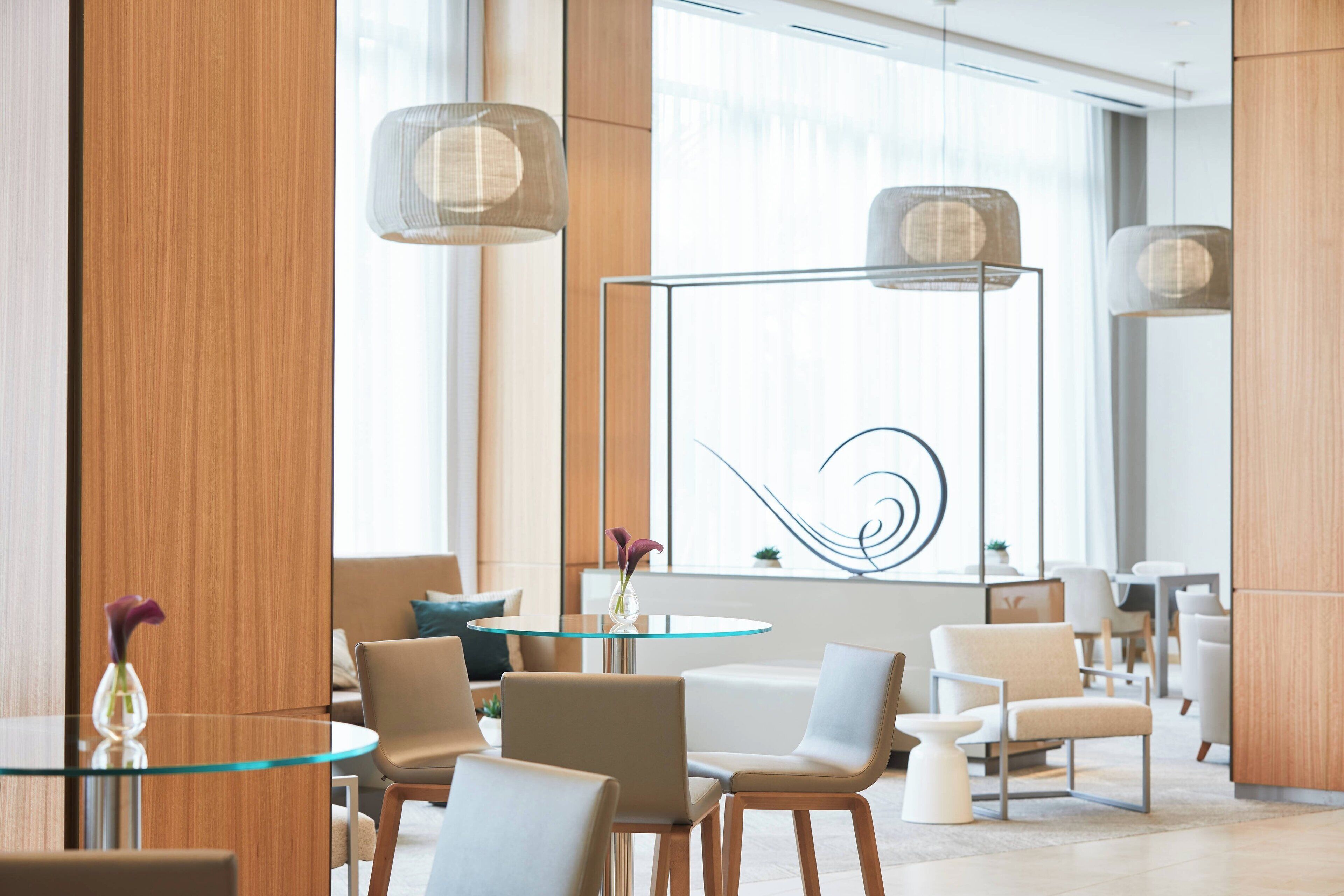 A modern hotel lobby with a glass table, comfortable seating, and decorative lighting.