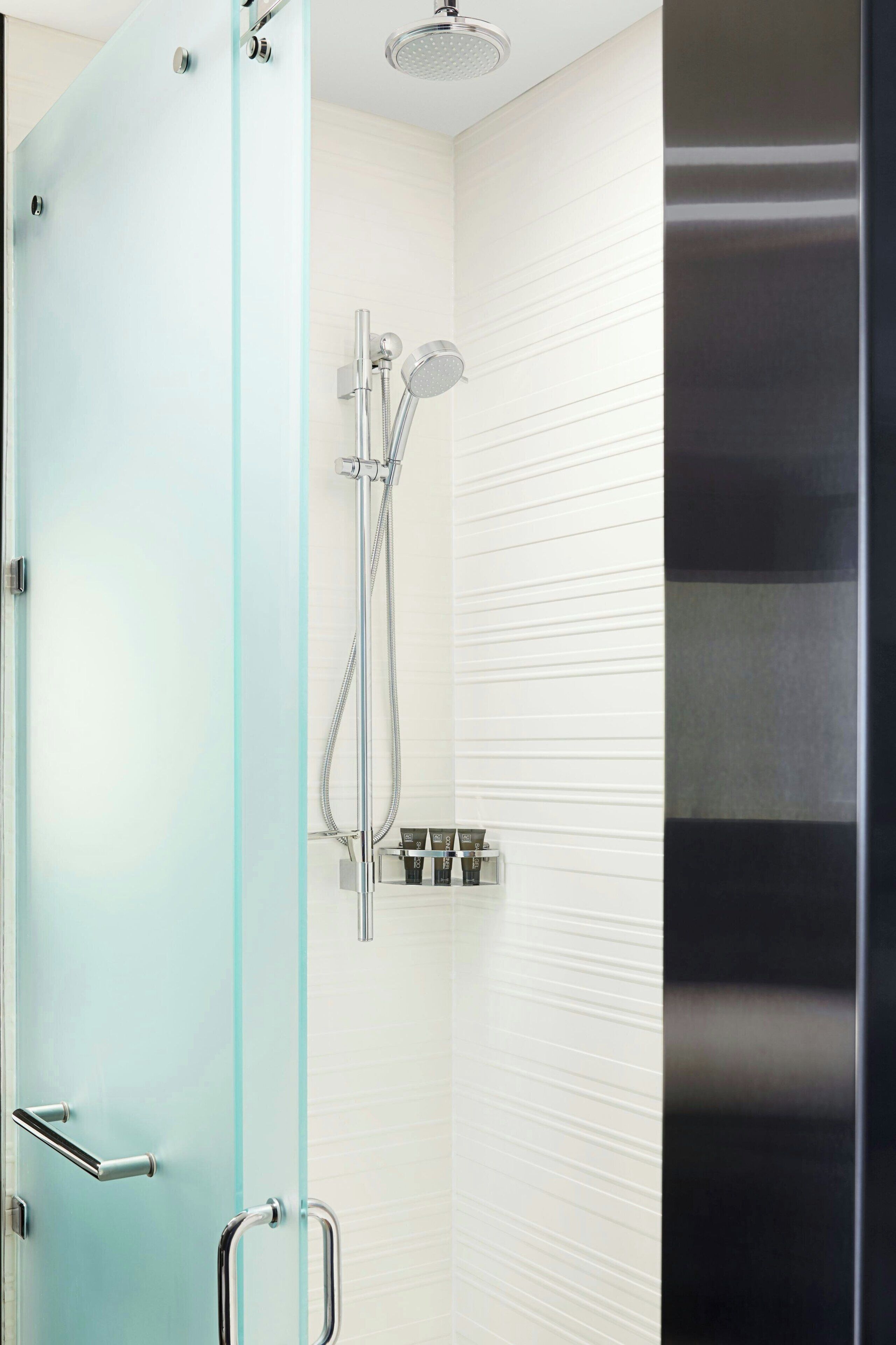 Un bagno moderno con box doccia in vetro, soffione a mano e pannello di controllo a parete.