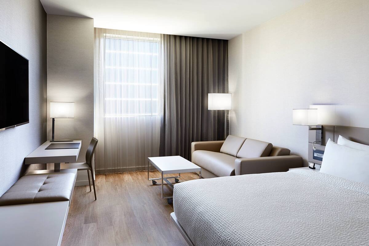 Une chambre d’hôtel moderne équipée d’un lit, d’un canapé, d’un bureau et d’une télévision.