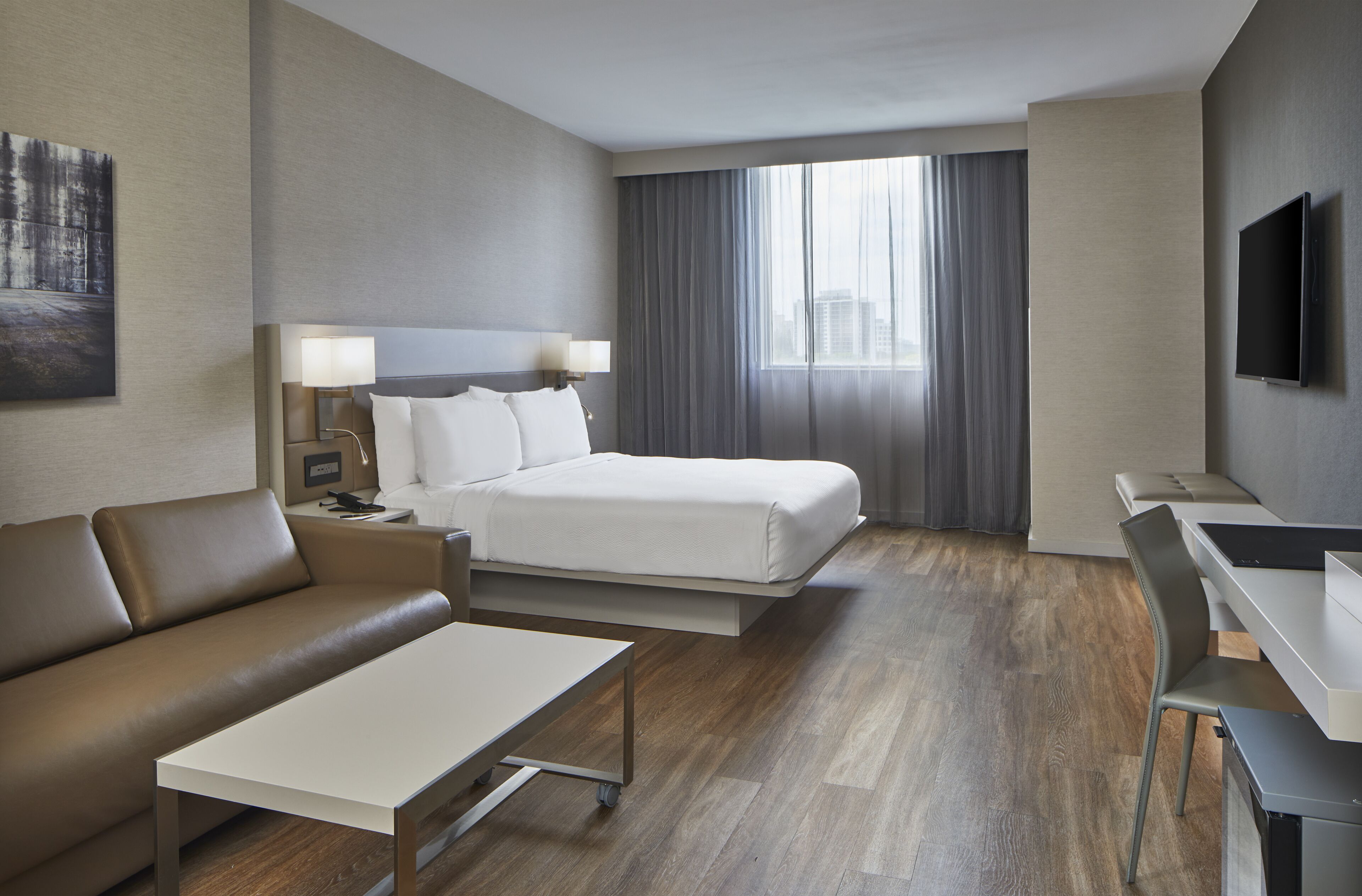 Une chambre d’hôtel moderne équipée d’un lit, d’un canapé, d’un bureau et d’une télévision.