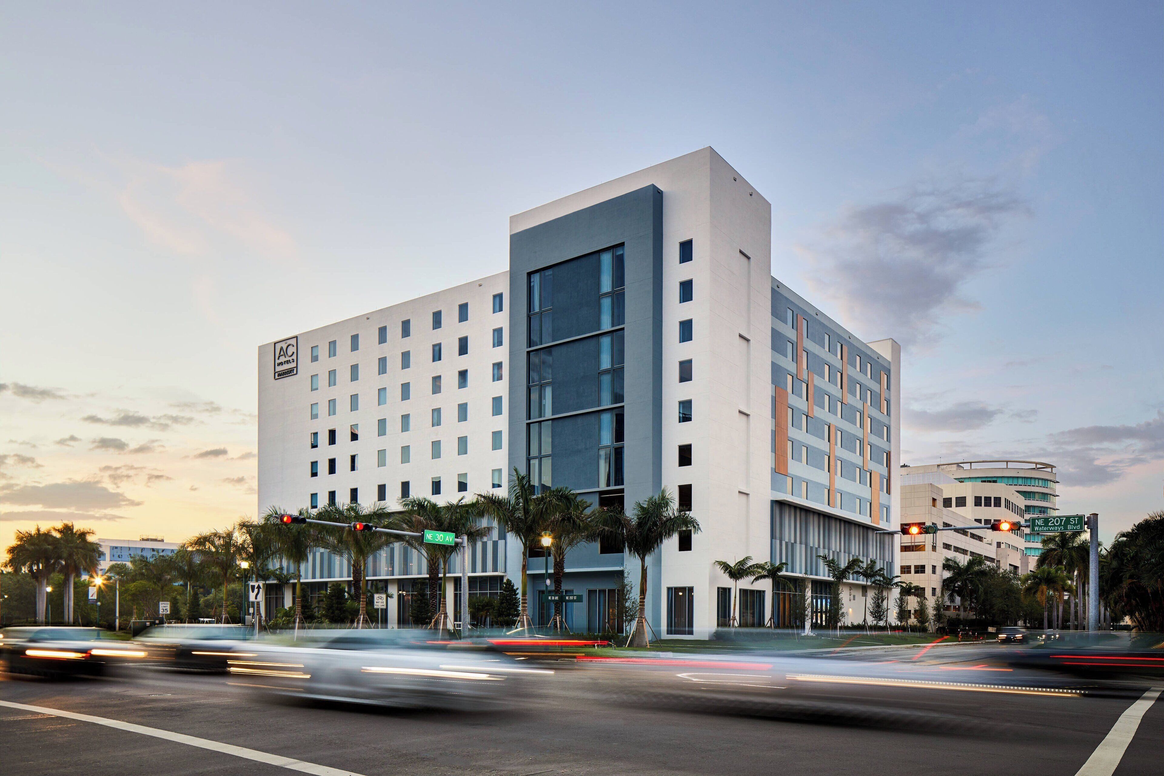 A modern hotel with a prominent glass facade, multiple floors, and a flat roof.