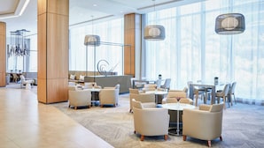 A spacious lobby with modern furniture, large windows, and hanging pendant lights.