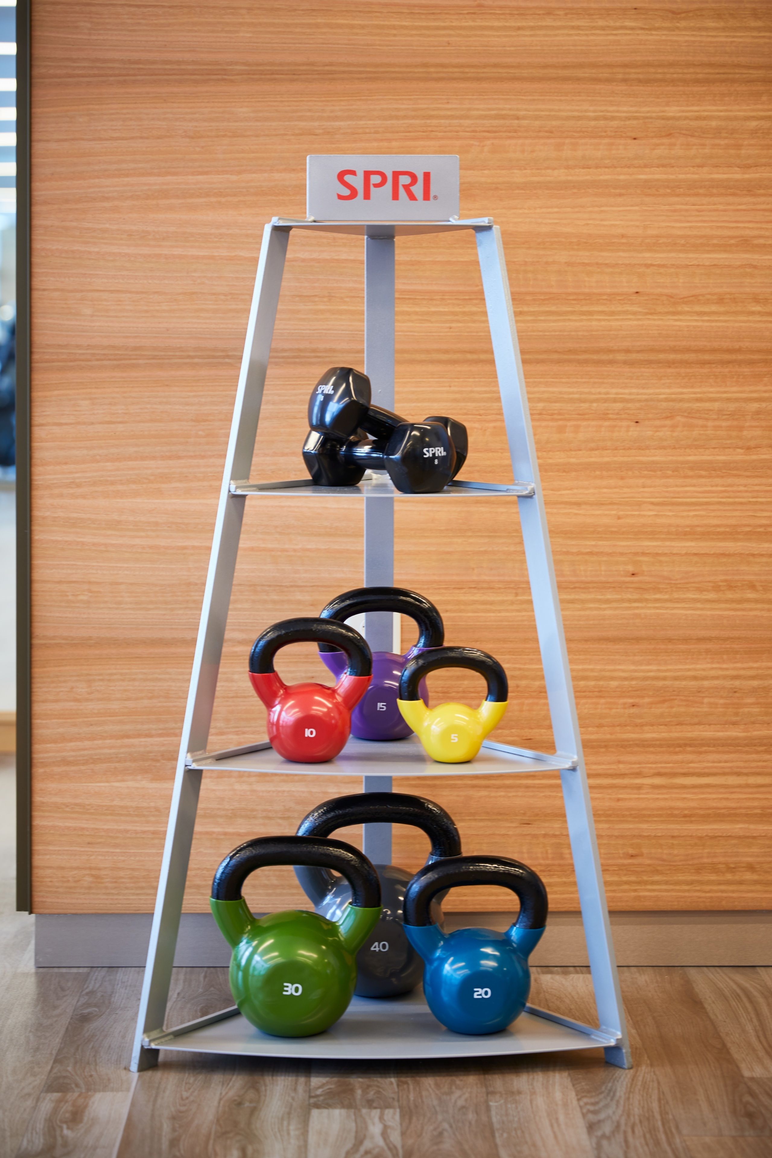 A metal rack with kettlebells of various weights and colors.