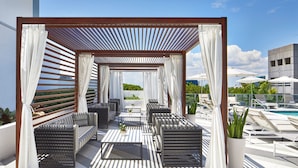 A rooftop lounge with outdoor seating, a pool, and a view of the city skyline.