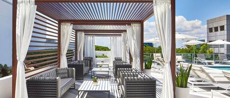 Un lounge en la azotea con asientos al aire libre, piscina y vistas del horizonte de la ciudad.