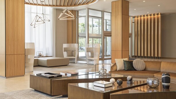 A modern living room with a glass coffee table, a sofa, and a large window.
