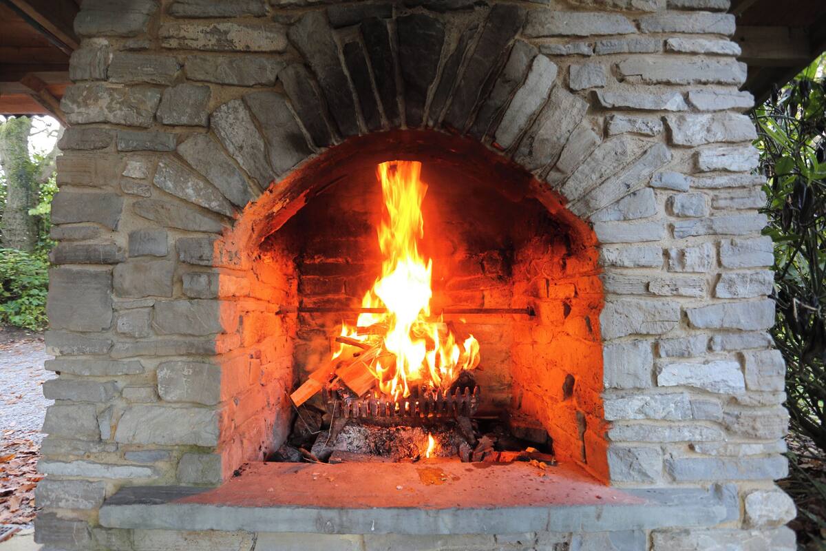A stone-built fireplace with a fire burning inside.