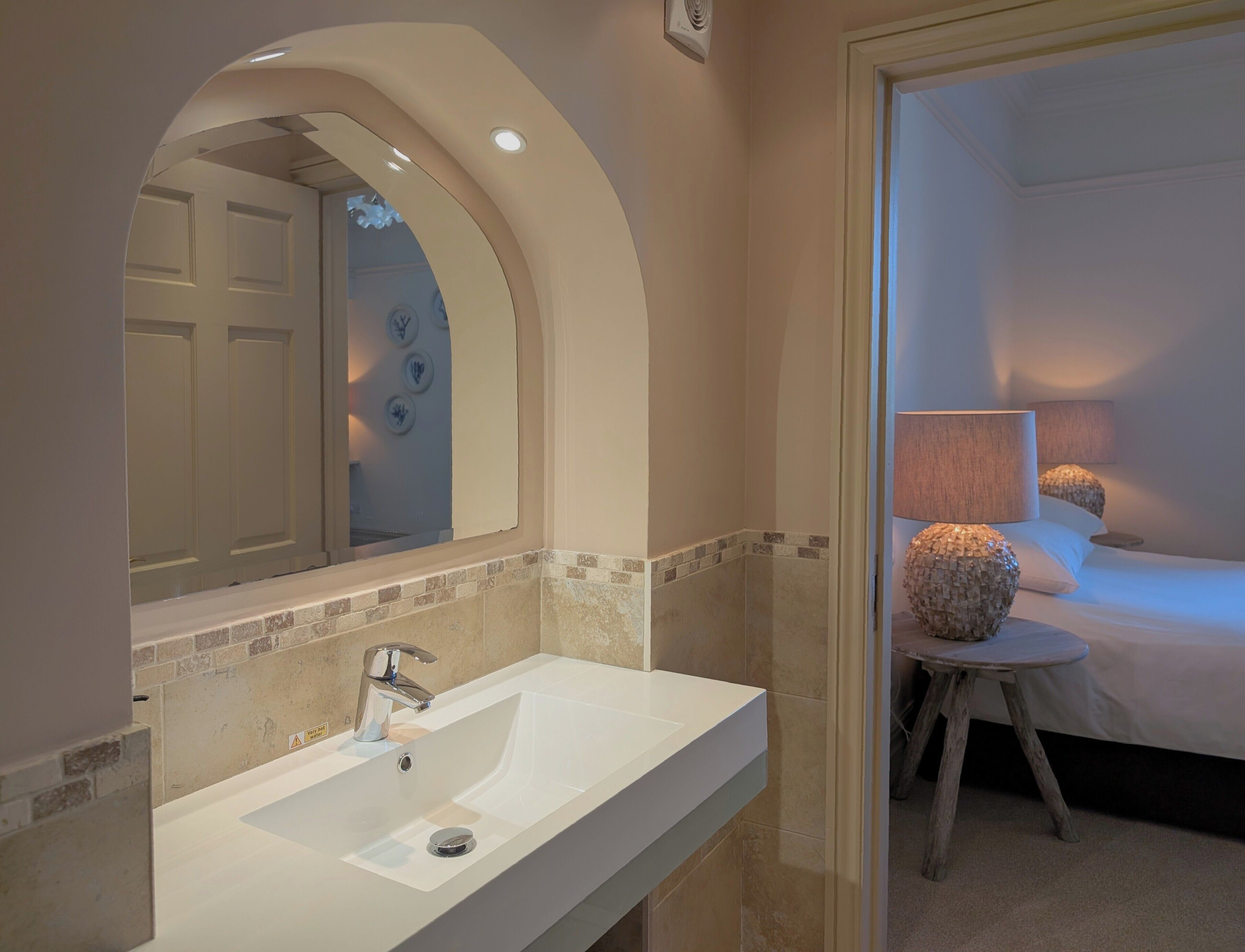 A bathroom with a white sink, a mirror, and a shower area.
