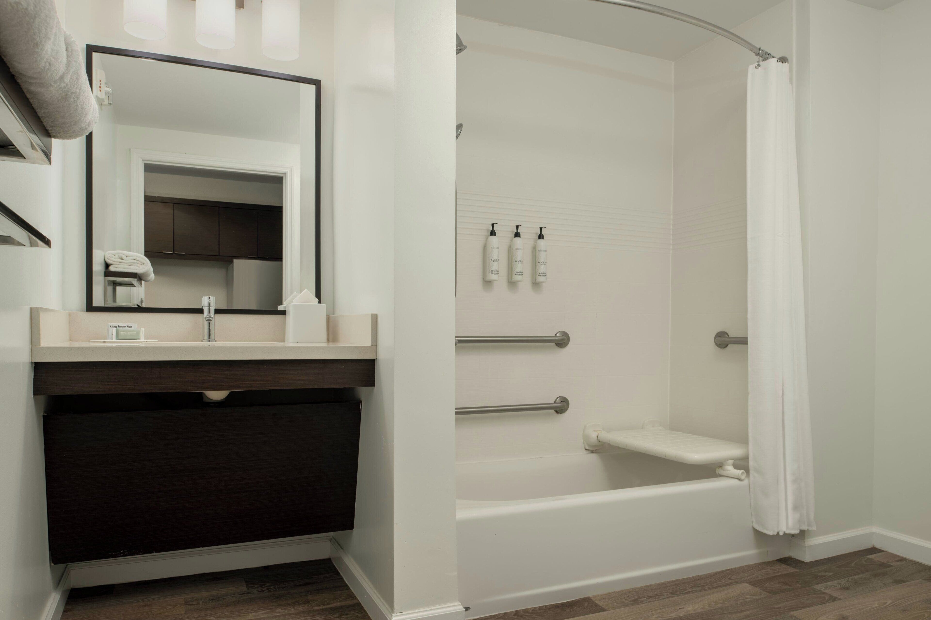 Un baño moderno con bañera, ducha, tocador con espejo y barra para toallas.
