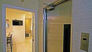 An interior space with a dining area, a television mounted on the wall, and an elevator with a control panel. - Rio Spot Apartments U033 (Rio de Janeiro)
