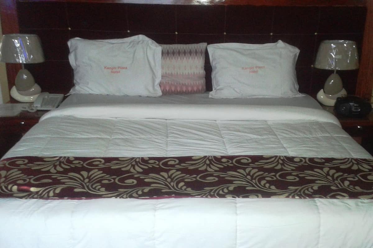 A neatly made bed with a patterned bedspread, two pillows, and a headboard.