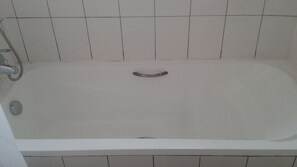 Una bañera blanca estándar con un solo grifo y desagüe.