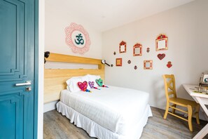 A bedroom with a wooden headboard, white bedding, a desk with a chair, and decorative wall art including a mandala and framed pictures. - La Palomilla - Boutique Stays with Mexican soul (Mexico City)