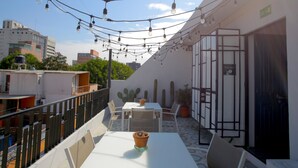An outdoor patio with a table and chairs, string lights overhead, and cacti in the background. - La Palomilla (Mexico City)
