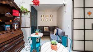 A cozy living area with a wooden dresser, a small round table with chairs, a grey sofa, and decorative wall lights. - La Palomilla (Mexico City)