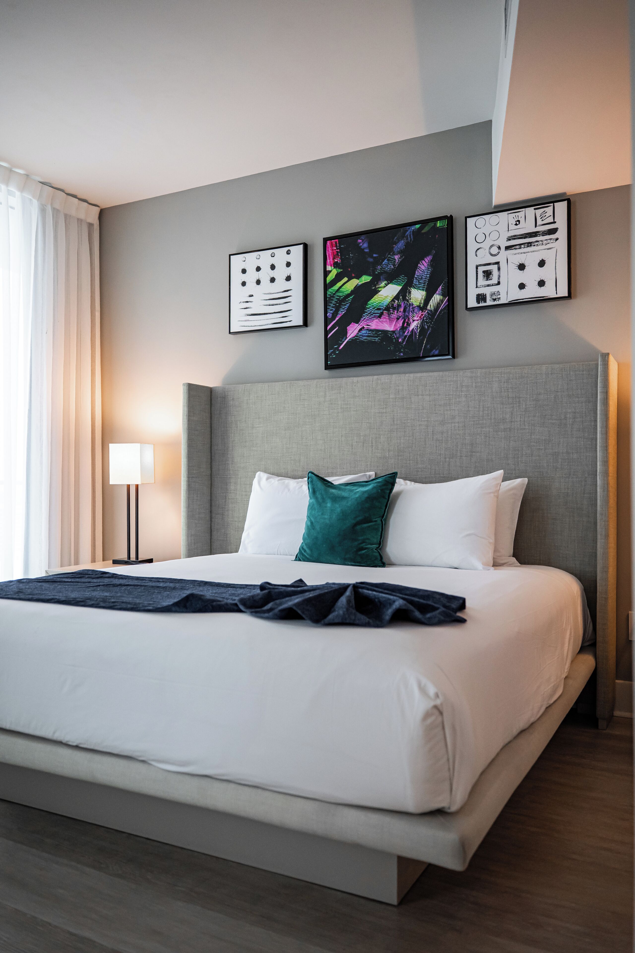 Habitación de hotel con una cama grande, cabecera y tres obras de arte enmarcadas en la pared.