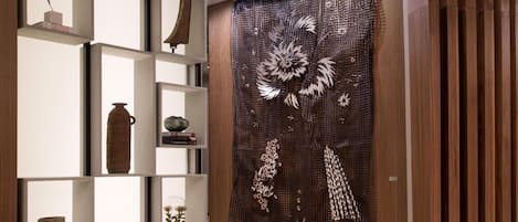 A modern interior with a wooden panel wall, a decorative metal sculpture, and a minimalist shelving unit with various objects.
