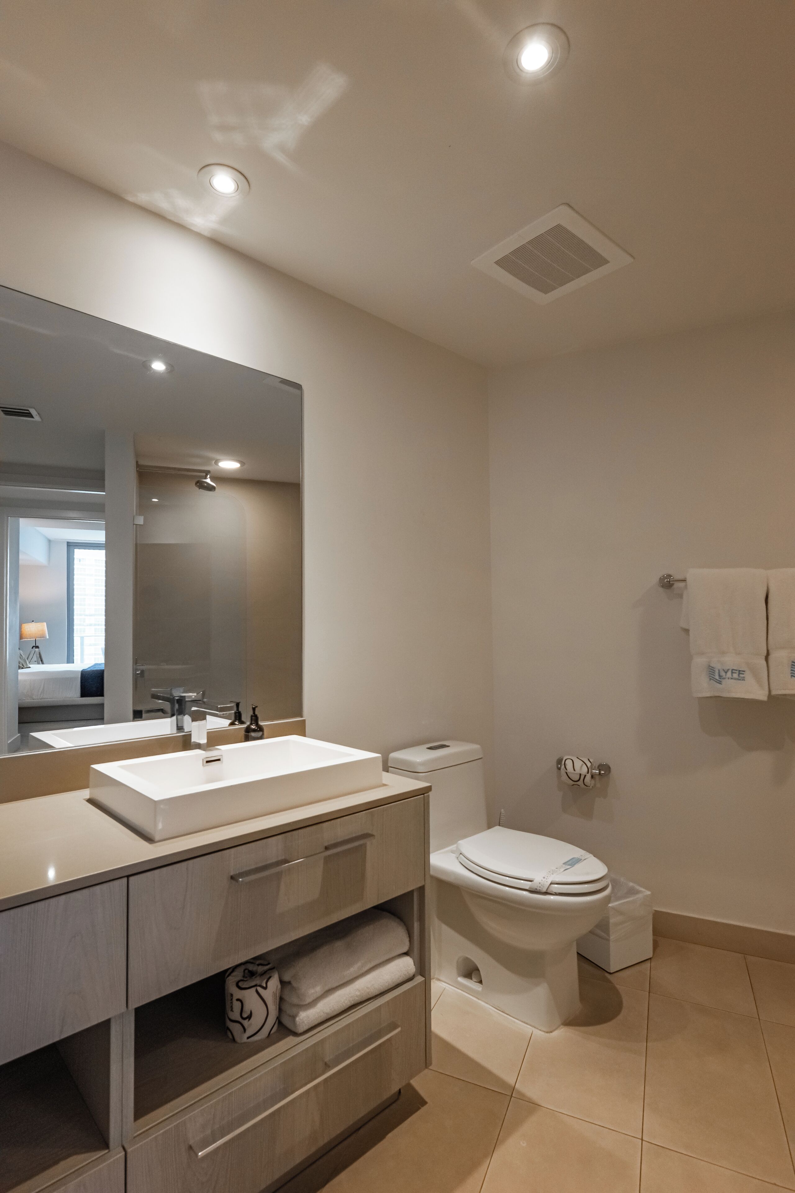 Une salle de bain moderne avec un grand miroir, un lavabo, des toilettes et un porte-serviettes.