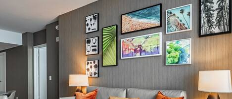 Una sala de estar moderna con un sofá gris, cojines naranja, una mesa de centro de madera y un televisor montado en la pared.