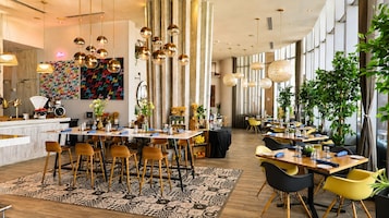 A spacious dining area with multiple tables and chairs, a patterned rug, and hanging spherical light fixtures.