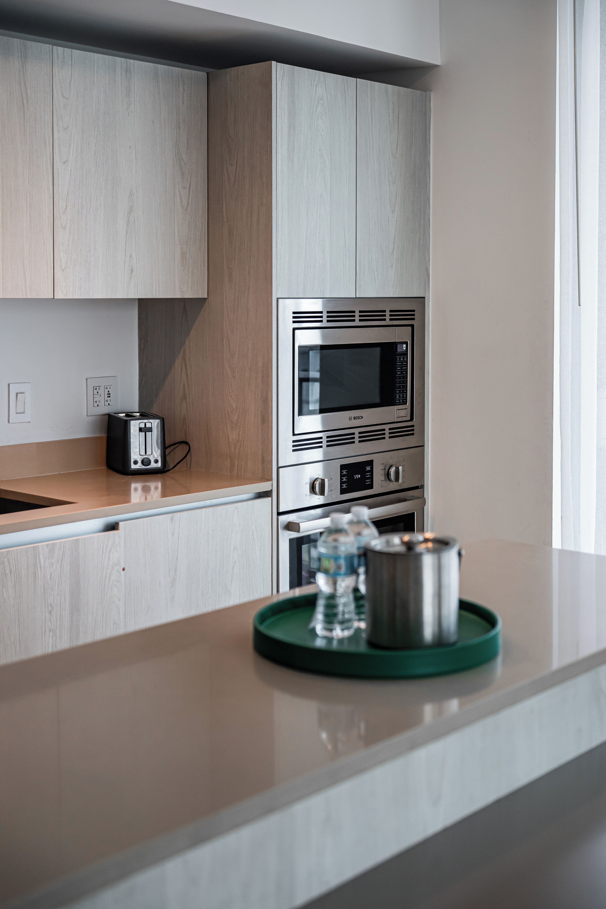 A modern kitchen with stainless steel appliances, a toaster, and a water bottle on the counter.