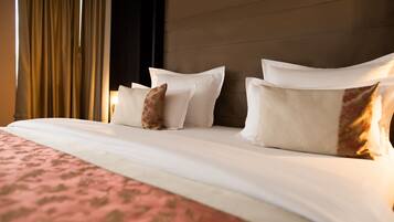 Un lit bien fait, avec du linge de lit blanc et des coussins décoratifs, une couvre-lit à motifs et une tête de lit en bois.