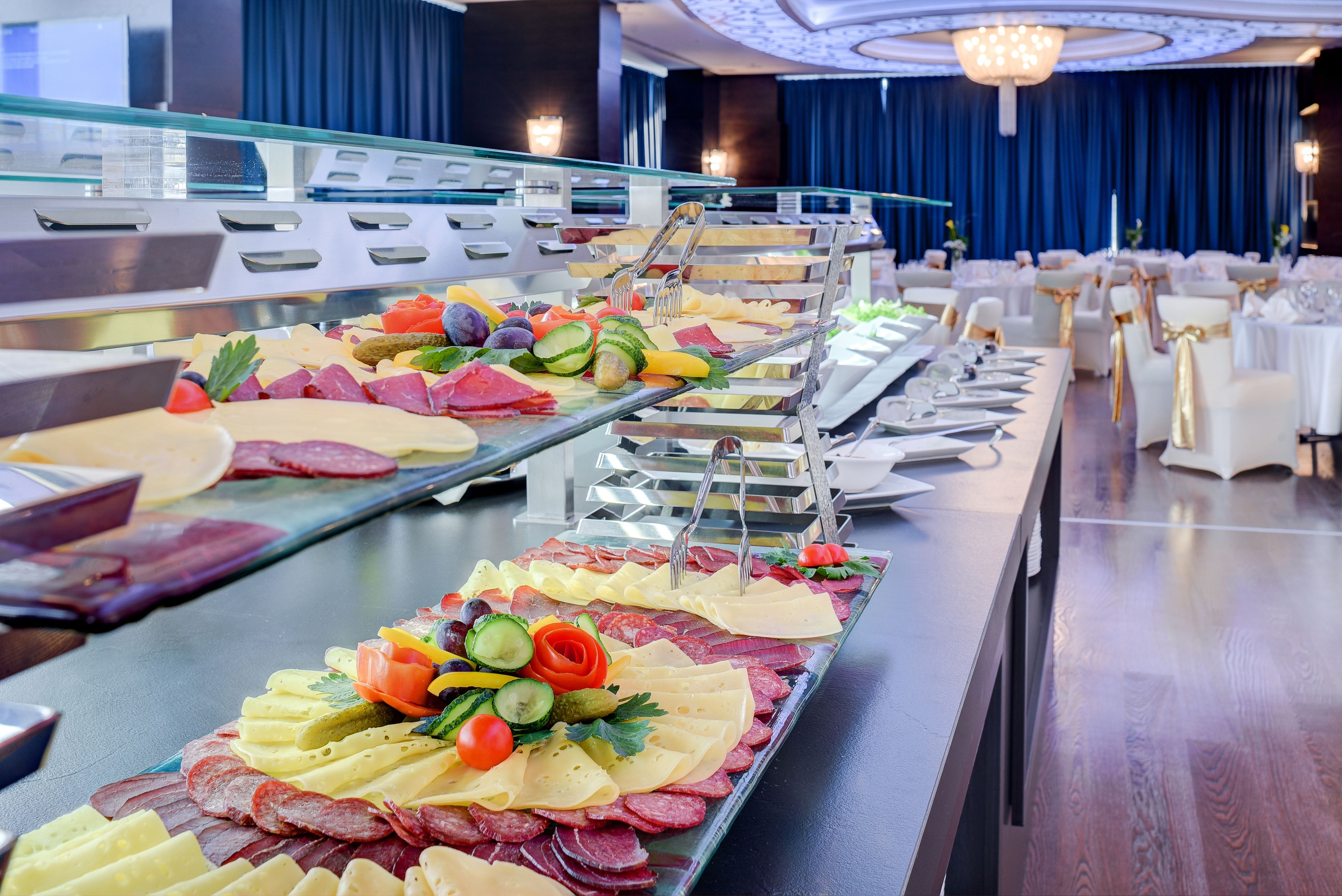 A buffet with various meats, cheeses, and vegetables.