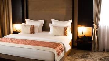 A hotel room with a large bed, two bedside tables with lamps, and a view of the outside through curtains.
