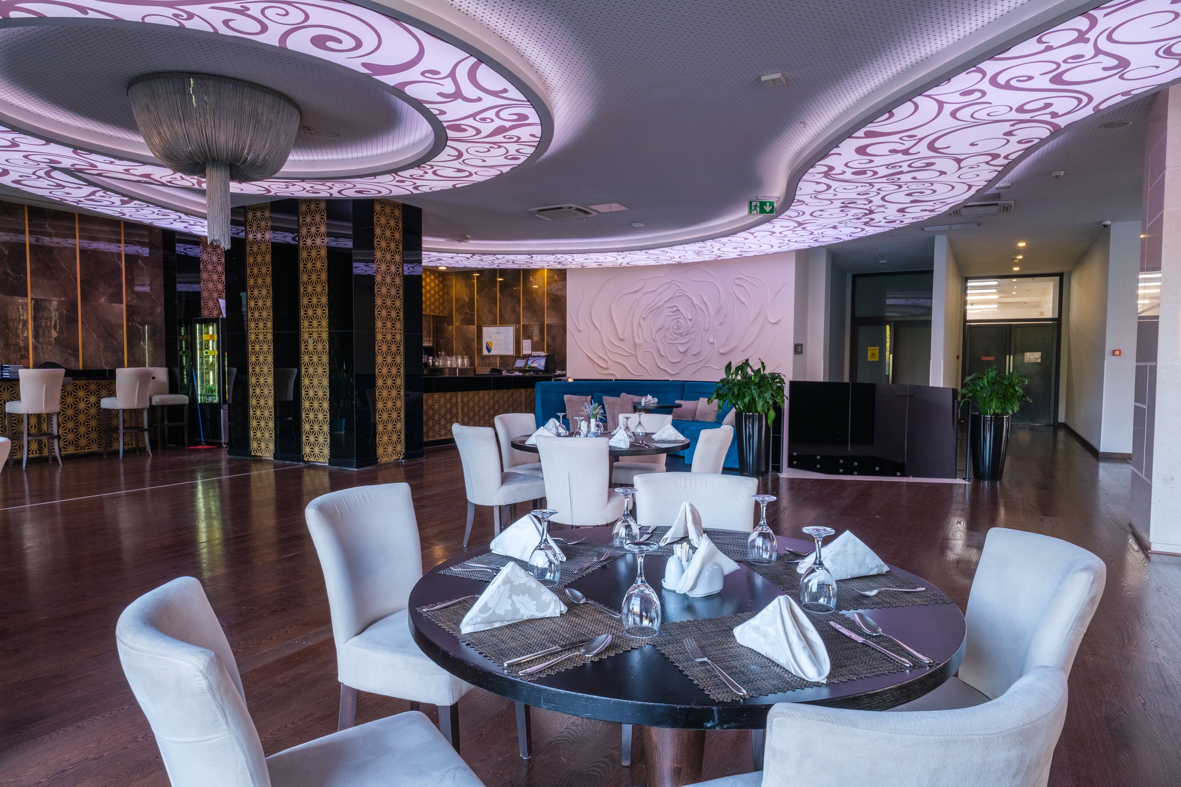A modern hotel lobby with a round dining table set for four, surrounded by white chairs.