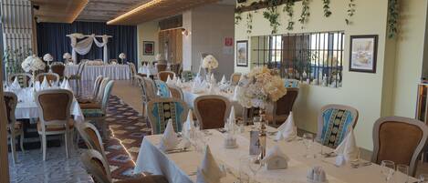 A banquet hall with round tables, chairs, and floral centerpieces.