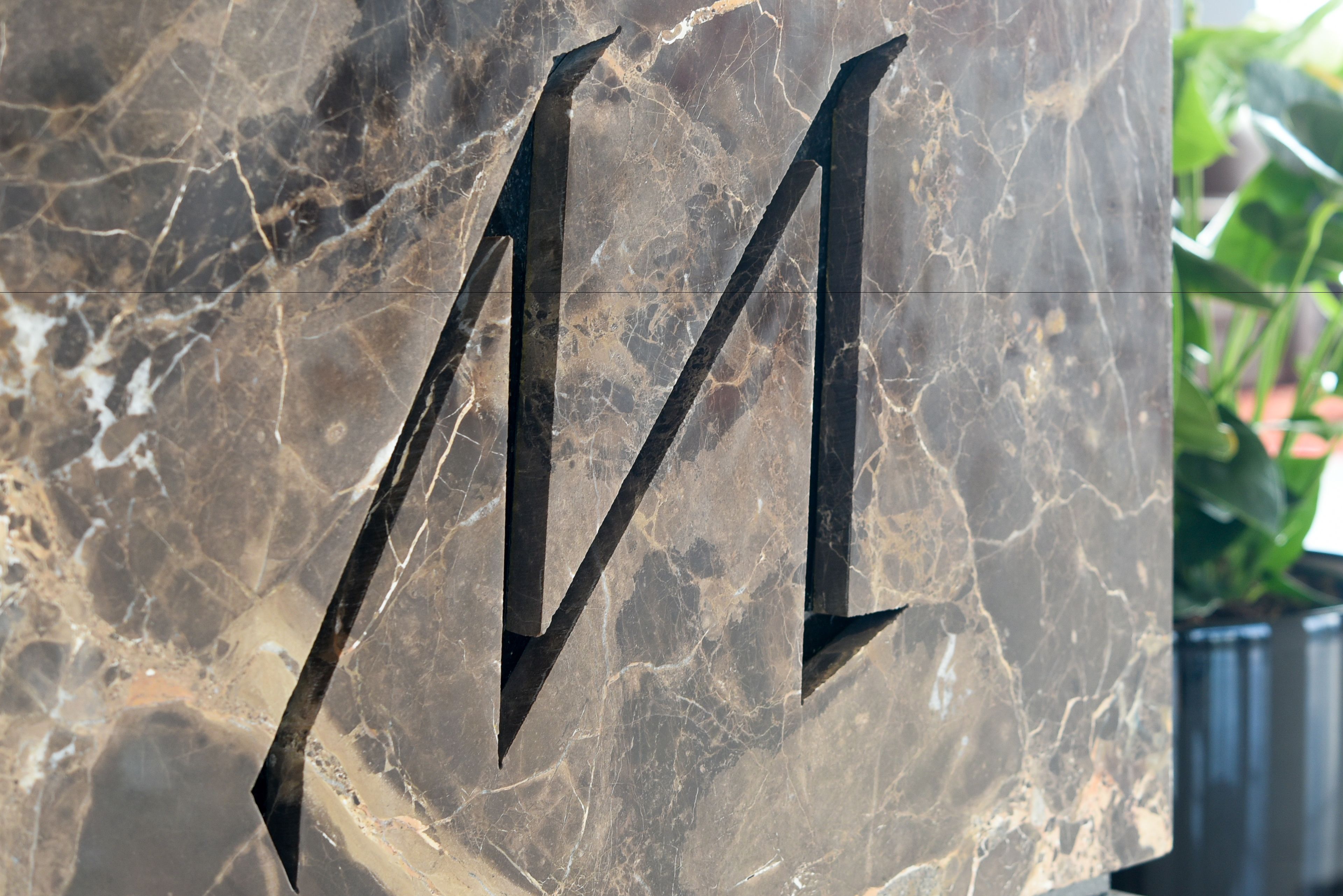 A marble wall with a large, dark letter 'M'.