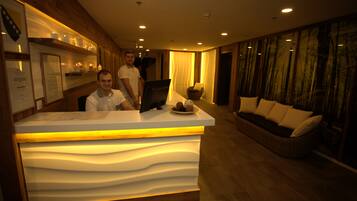 A reception area with a modern design, including a reception desk, a sofa, and a wall with framed certificates.