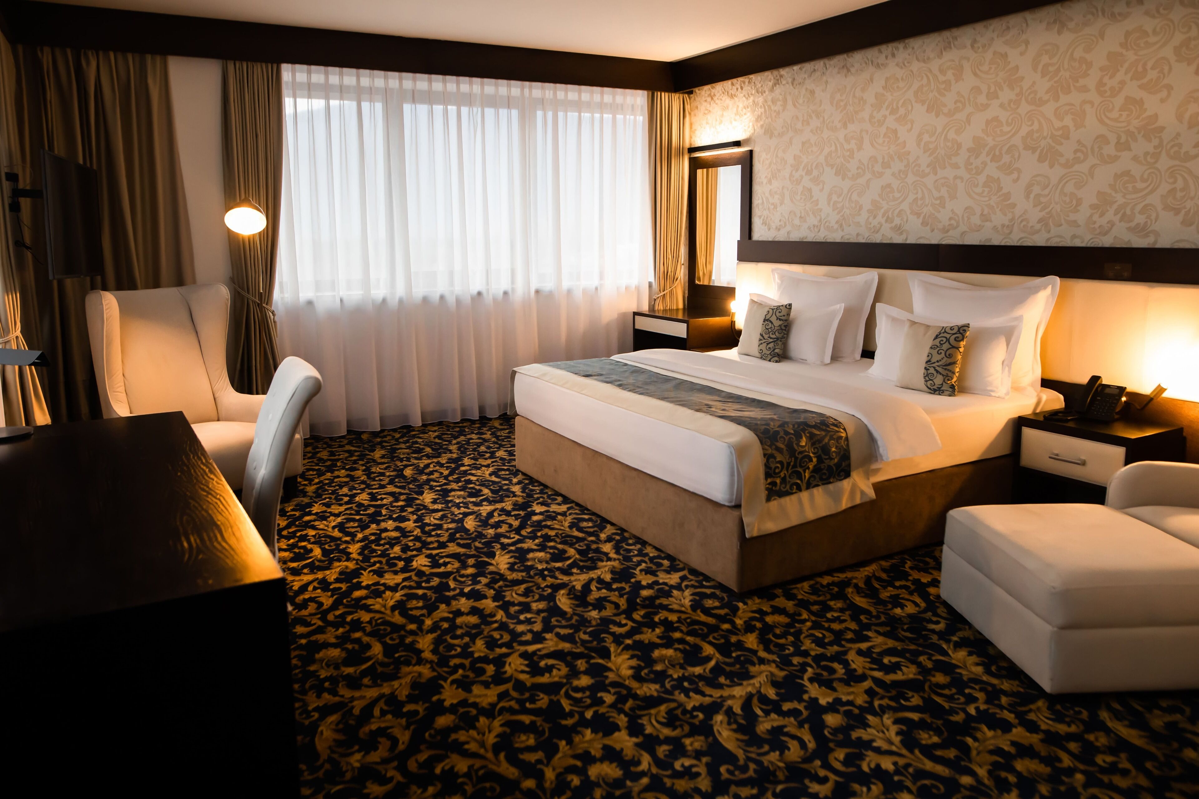 Ein Hotelzimmer mit einem großen Bett, einem Schreibtisch, einem Sessel, einem Nachttisch und einer Lampe.