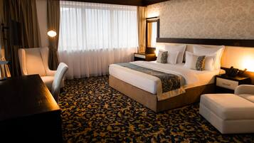 Ein Hotelzimmer mit einem großen Bett, einem Schreibtisch, einem Sessel, einem Nachttisch und einer Lampe.
